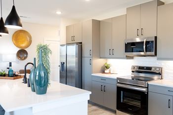 A modern kitchen with a white countertop and stainless steel appliances.